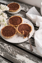 homemade chocolate tartlets, wooden backdrop, lilac, spring time