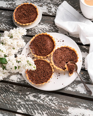chocolate tartlets, white lilac flowers, rustic style, on a wooden backdrop