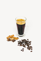 GLASS CUP OF COFFEE WITH CINNAMON ON WHITE BACKGROUND