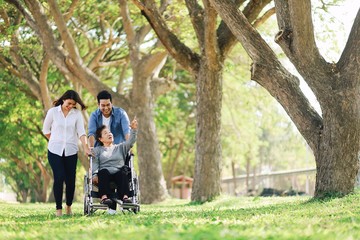 Elderly woman in wheelchair taking with her daughter and son in park
