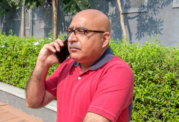 Indian man talking on mobile phone outdoors at Pune India.