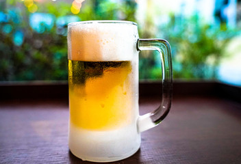 Beer. Frosty mug cold craft light ice bubble beer in a glass with water drops green bokeh background. drink alcohol celebration party holiday new year concept