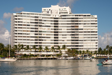 tall hotel like building basks in the warm sunlight next to a dock on a sunny day in Miami, Florida