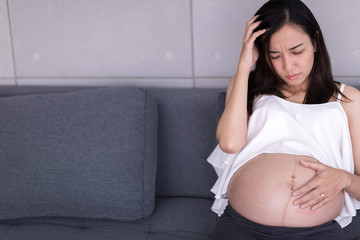 A pregnant woman sits as anxious about the child in her womb.