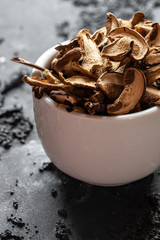 braune geschnittene gesammelte getrocknete Pilze auf grauem Grund im Herbst in einer weißen schale