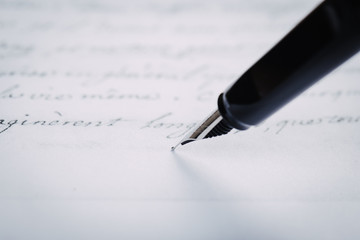 Fototapeta premium Fountain pen on an ancient handwritten letter. Old story. Retro style.