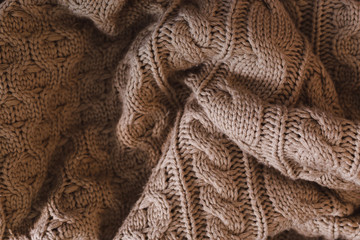 Obraz premium Crumpled gray beige knit blanket. Soft and warm fabric wrinkled in folds. Texture for background or illustration.