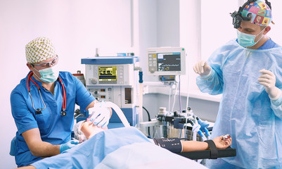 Several doctors surrounding patient on operation table during t