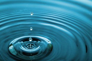 Closeup Water drop falling on the surface of the water and beautiful circular wave ripple, fresh natural mineral water drink water concept