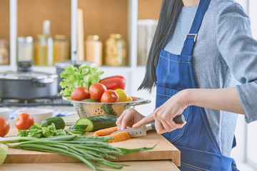 A young woman prepares food in the kitchen. Healthy food - vege