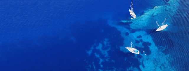 Aerial drone photo of sail boats docked in turquoise exotic island bay with crystal clear sea