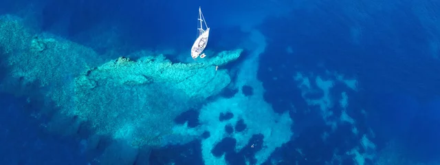 Luftdrohnenfoto von Segelbooten, die in einer türkisfarbenen exotischen Inselbucht mit kristallklarem Meer angedockt sind © aerial-drone
