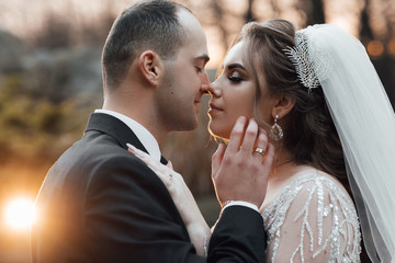 A happy couple on their wedding day, looking at each other and smiling. Bride and groom are standing face to face with the green hills on background. Wedding. Wedding couple love