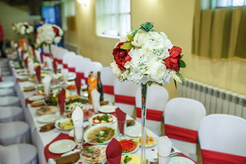 View of the served for decorated wedding dinner table in elite restaurant with beautiful flowers.