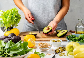 Woman holds half ripe avocado and knife. cooking healthy food concept.