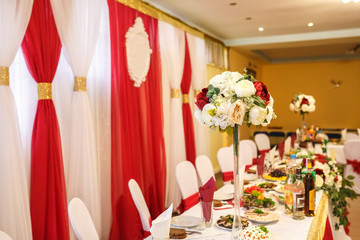 View of the served for decorated wedding dinner table in elite restaurant with beautiful flowers.