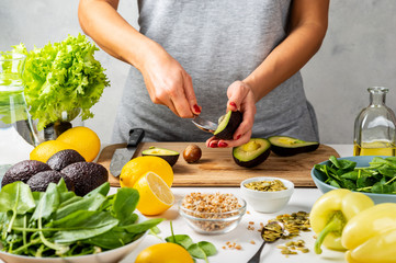Woman preparing avocado for eating in the kitchen. cooking healthy food concept.