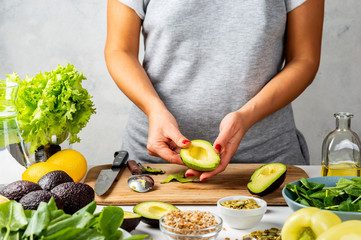 Woman peels avocado. cooking healthy food concept.