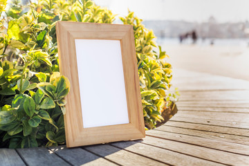 Wooden photo frame in front of bush