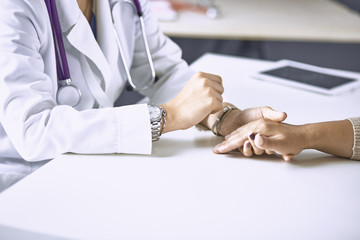 Woman doctor calms patient and holds hand