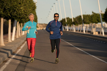 Two happy athletes jogging on the city street, Alicante, Spain