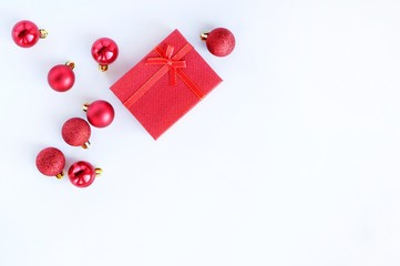 Red gift box and Christmas balls on a white background.Christmas, winter holidays, festive delivery concept. Top view, flat lay with copy space.