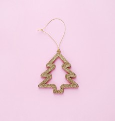 Christmas and New Year golden  decorative fir-tree on a pastel pink background. Minimalistic holiday concept. Square,top view, flat lay.