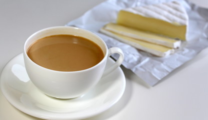 Coffee with milk. White cup. Soft brie cheese. Morning. Tasty breakfast.