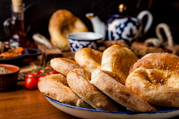 Traditional oriental cuisine. Uzbek cake made of yeast dough with a pattern. Baked in the oven. Serving dishes in Uzbek plates. Copy space, background image