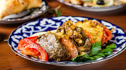 Traditional oriental cuisine. Dish for the holiday of Navruz from meat, fish, pineapple, paprika, tomato and lemon. Serving dishes in Uzbek plates. Copy space, background image