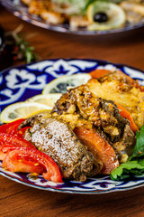 Traditional oriental cuisine. Dish for the holiday of Navruz from meat, fish, pineapple, paprika, tomato and lemon. Serving dishes in Uzbek plates. Copy space, background image