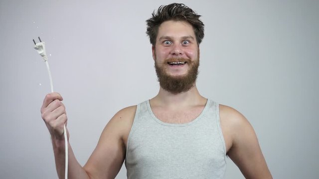 The guy's holding a sparking power cord and smiling
