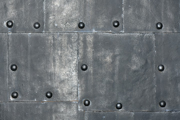 Metal wall with rivets. Faded shiny