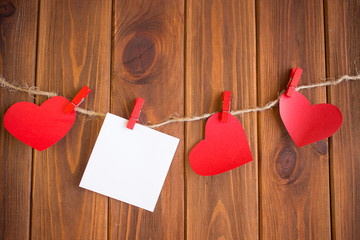 Red hearts are held by clothespins on a jute rope, on a dark wooden background. Copy space.Valentine's Day