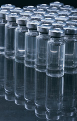 Glass medical ampoule vial for injection. Medicine is dry white drug penicillin powder or liquid with of aqueous solution in ampulla. Close up. Bottles ampule with aluminum cap on backgrounds gray.