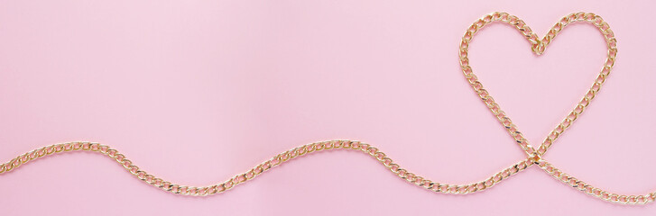 a gold chain laid out in the shape of a heart on a pink background
