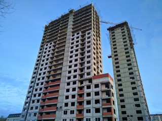 Construction of a multi-storey monolithic house of gray concrete against the blue sky