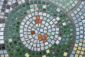 The circle of mosaic tiles on the wall of the building, the tiles are green and gray. Close-up stock photo.