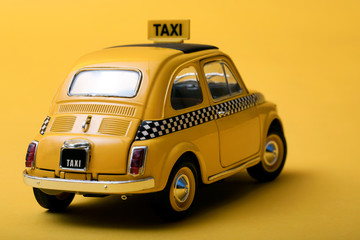 Obraz na płótnie Canvas Yellow retro toy taxi on yellow background