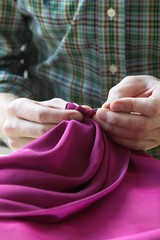 Closeup Of Tailor Sewing Fabric At Table