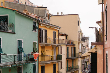 Fototapeta na wymiar Wooden shutters on a bright Italian houses. Balconies and a narrow Italian street
