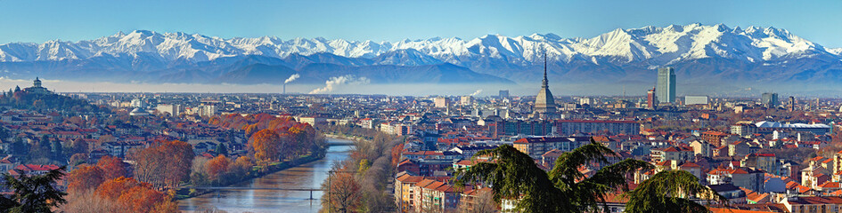 Aerial panoramic winter view on Turin city center with Mole Antonelliana, modern skyscrapers and other buildings, clear blue sky morning with Alps full of snow on background