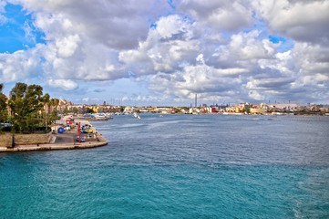 Panoramic seafront view of the old town of Taranto overlooking the Mar Piccolo, with fishing boats, jetties and facades of ancient buildings