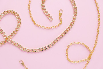 a gold chain laid out in the shape of a heart on a pink background
