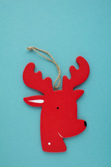Christmas decoration red wooden reindeer at blue background. New year flat lay.