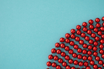 New year flat lay. Christmas decoration red beads at blue paper background. Abstract festive backdrop with copy space.