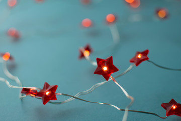 Blurred new year background. Christmas garland with red decorative shining stars at blue background.