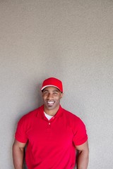 Portrait of a happy African American delivery man against wall