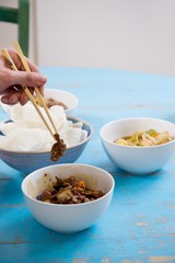 Close of human hand with chopsticks holding food
