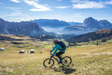 Young man with mountain bike cycling on Seceda mountain peak at sunrise. Puez Odle, Trentino, Dolomites, Italy.